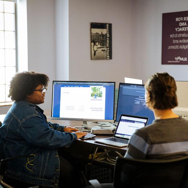妇女与性别研究专业的学生在台式电脑上交谈和打字.